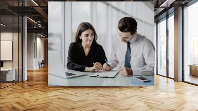 Two young happy smiling successful businesspeople working with document or contract at office. Success in business and teamwork concept. Wall mural